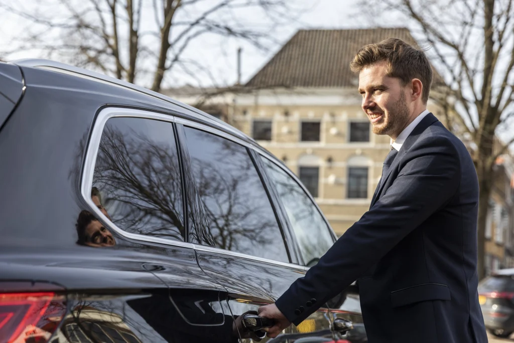 Chauffeur van Taxi Stam bij een auto voor een historisch pand