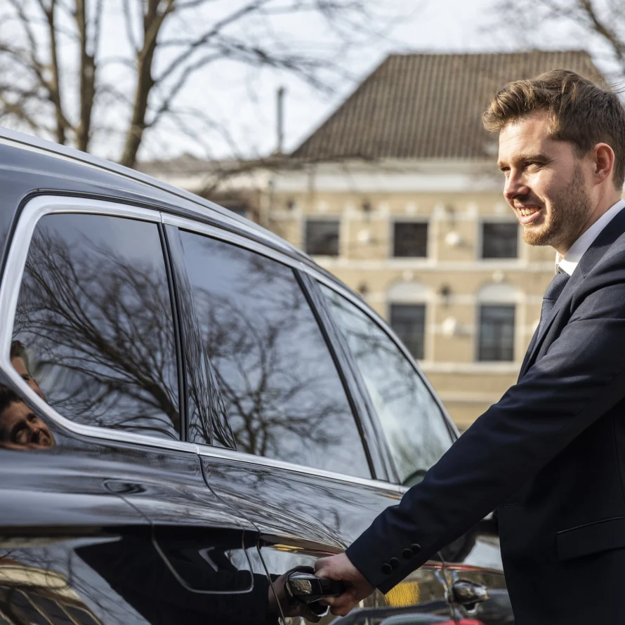 Chauffeur van Taxi Stam bij een auto voor een historisch pand