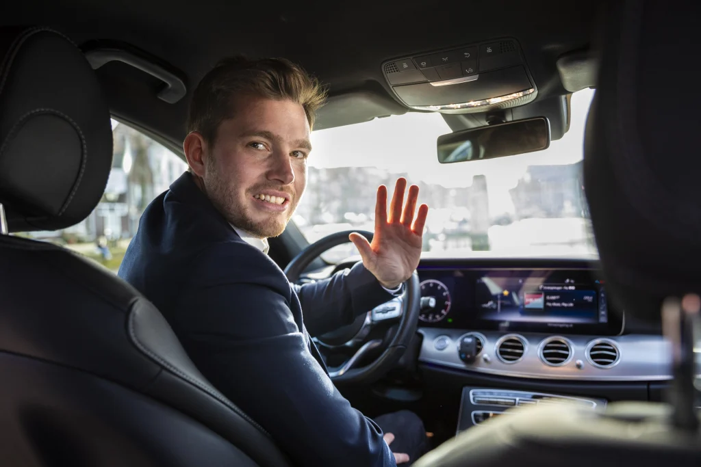 Zwaaiende chauffeur achter het stuur