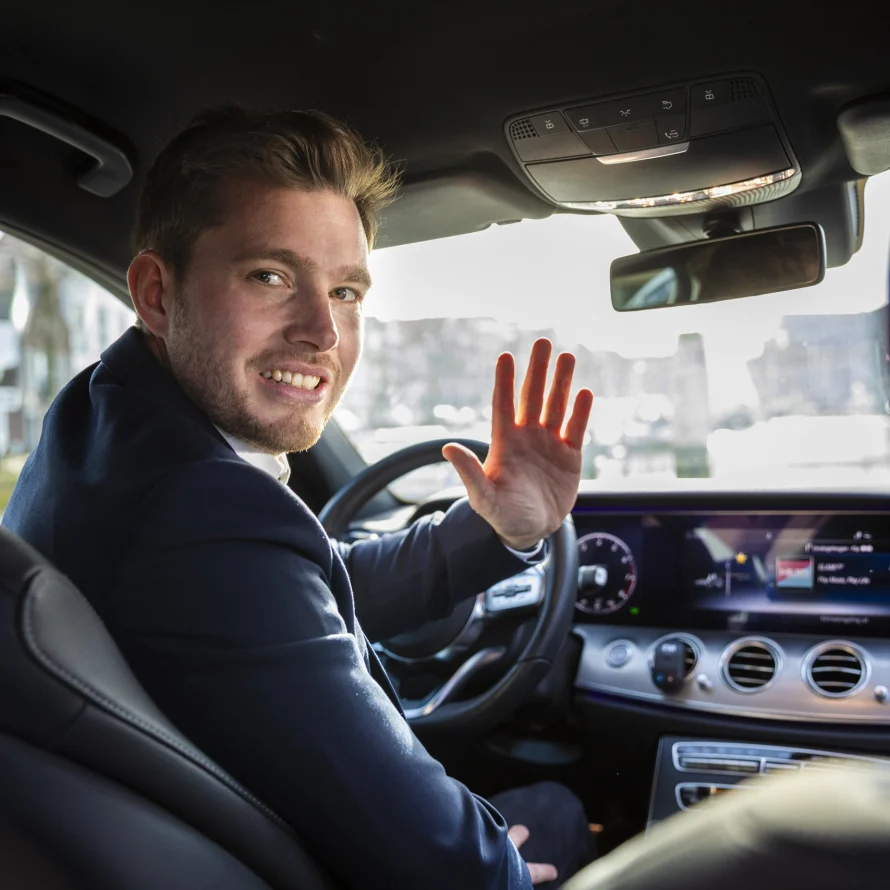 Zwaaiende chauffeur achter het stuur