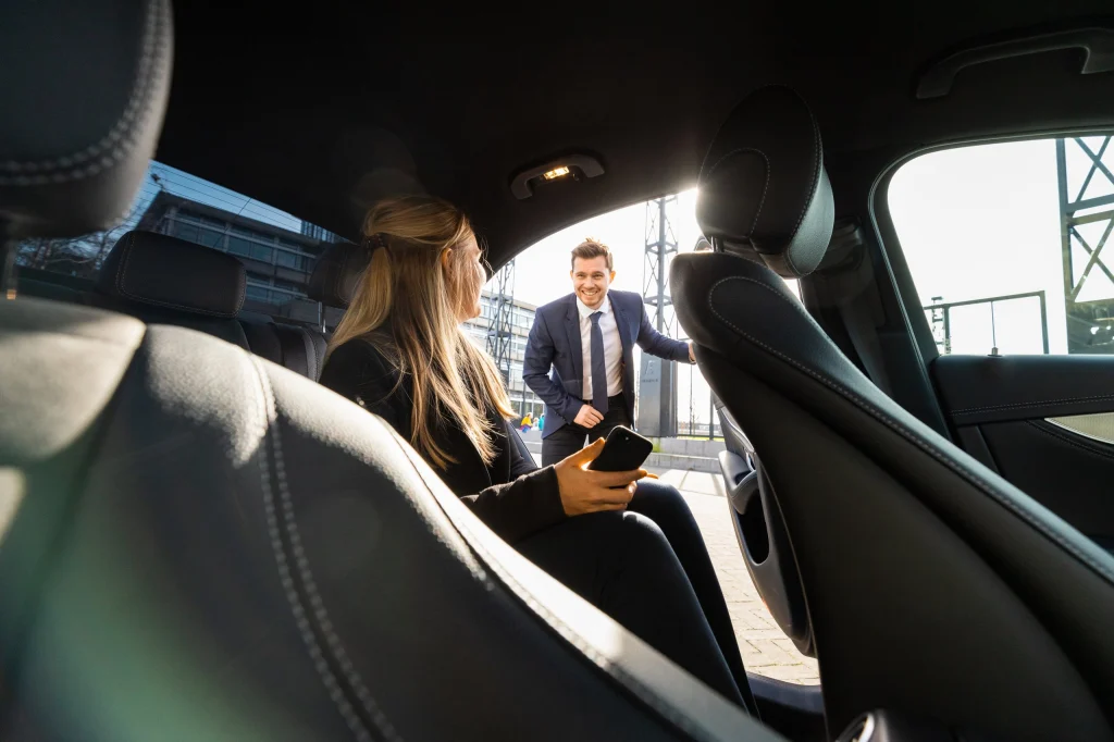 Passagier op de achterbank terwijl de chauffeur buiten klaarstaat