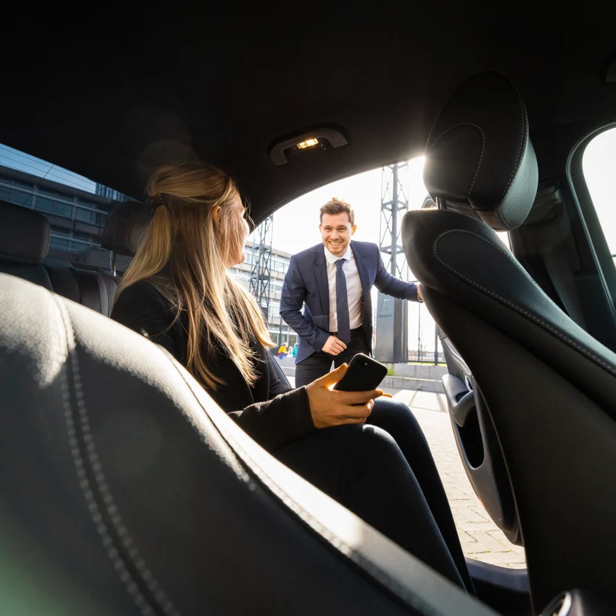 Passagier op de achterbank terwijl de chauffeur buiten klaarstaat