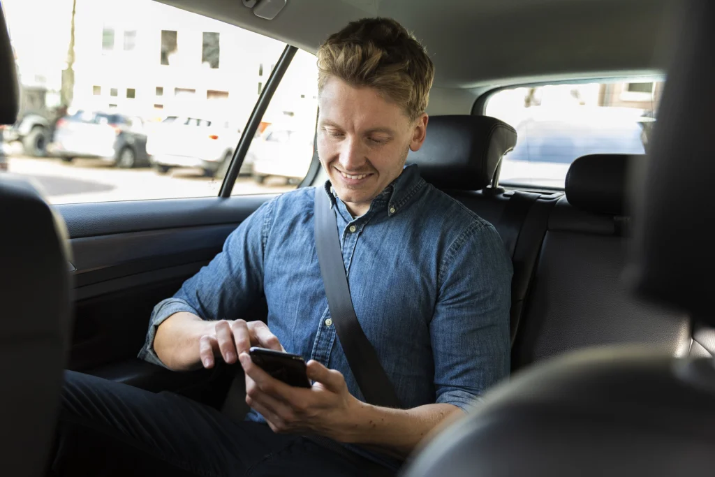 Passagier met telefoon op de achterbank van de taxi