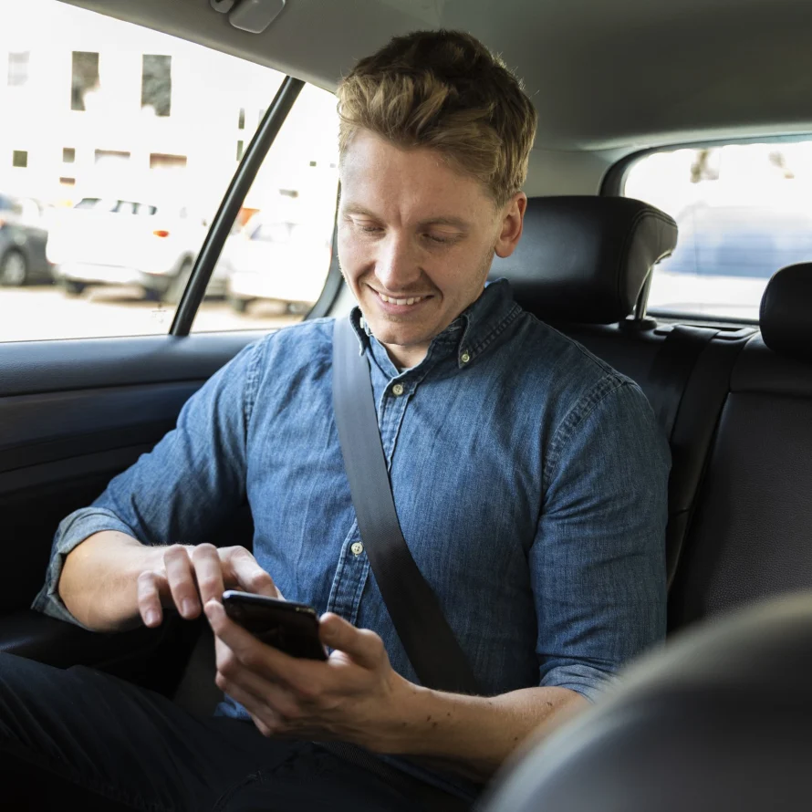 Passagier met telefoon op de achterbank van de taxi