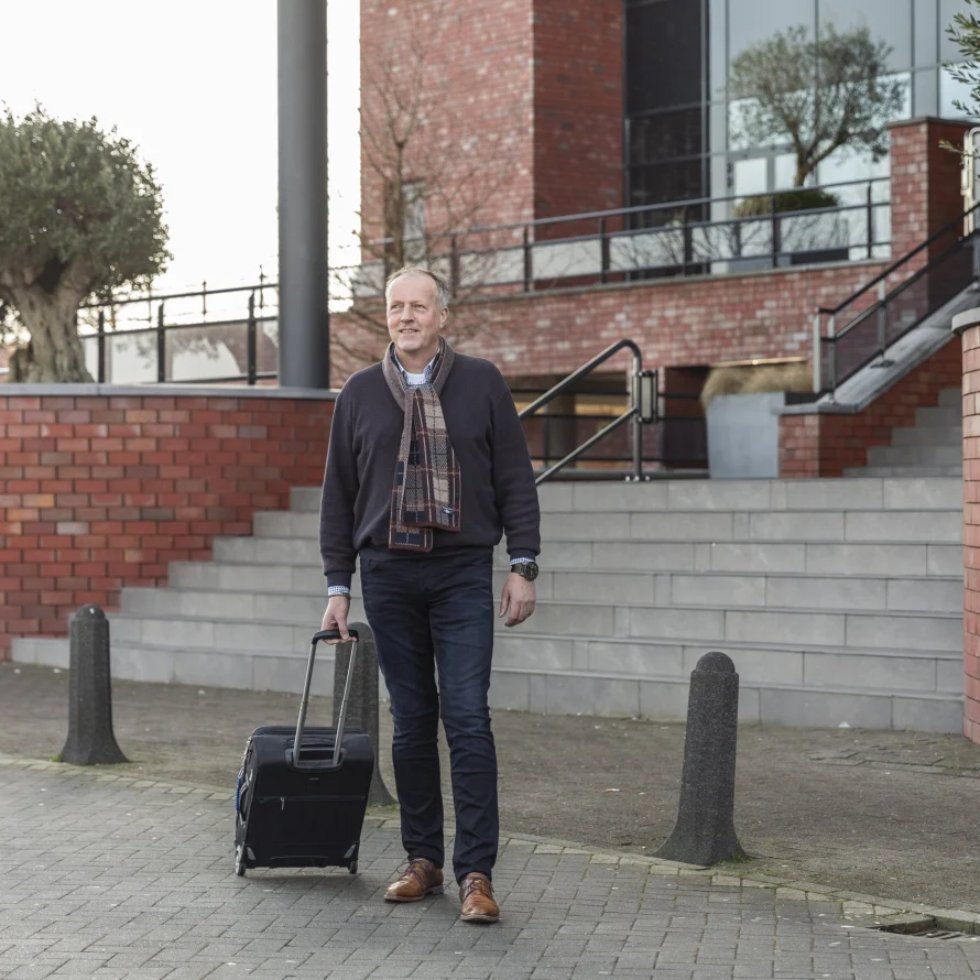 Reiziger met rolkoffer loopt naar de taxi