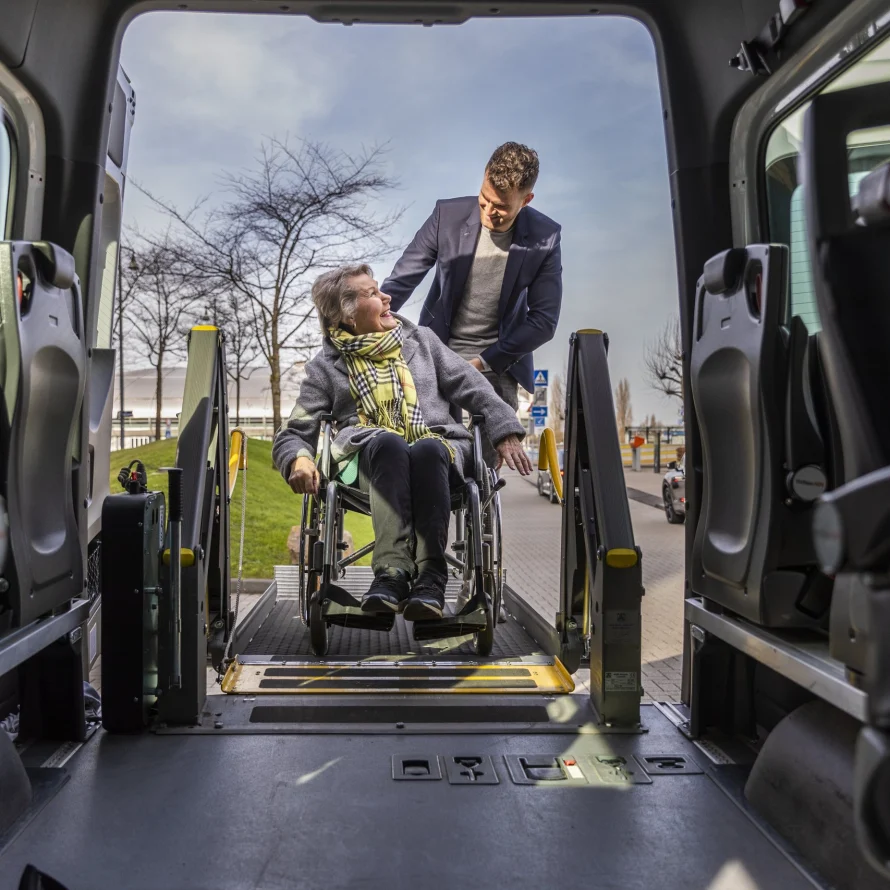 Zicht vanuit de rolstoelbus op een passagier in een rolstoel op de lift