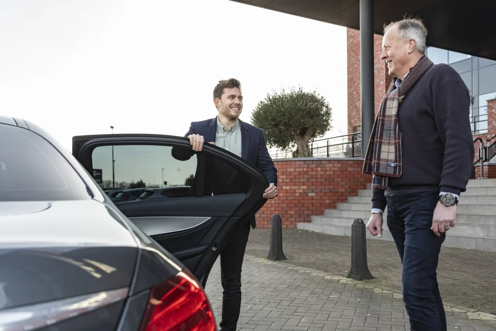 Chauffeur houdt het portier open voor een passagier