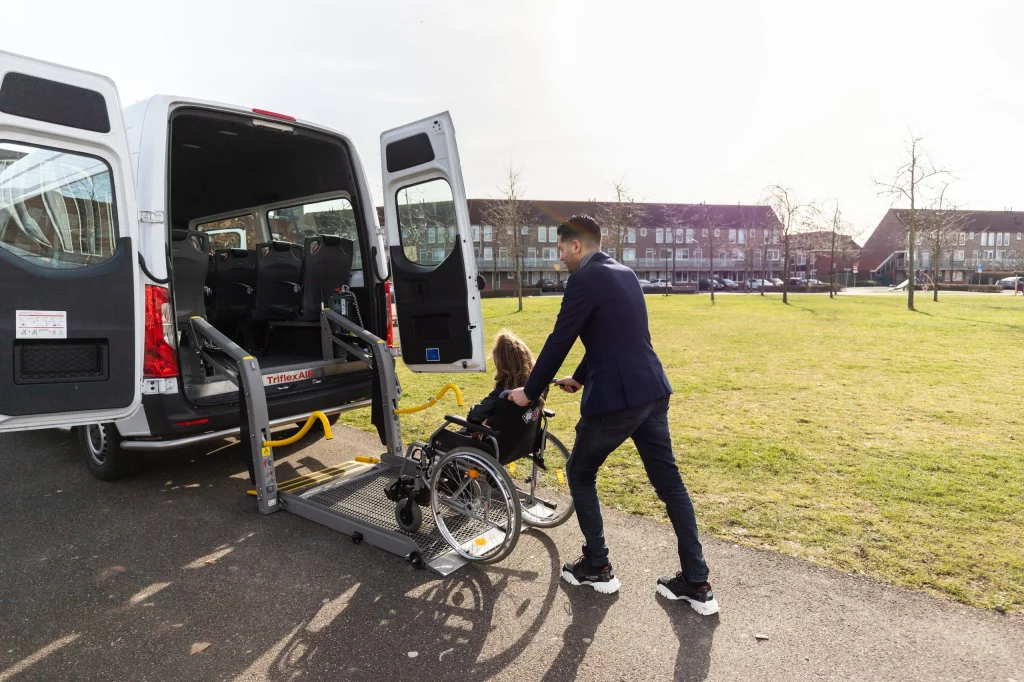 Chauffeur duwt een passagier in een rolstoel naar de bus