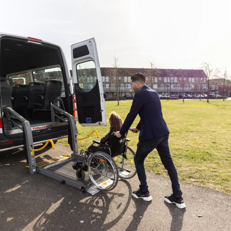 Chauffeur duwt een passagier in een rolstoel naar de bus