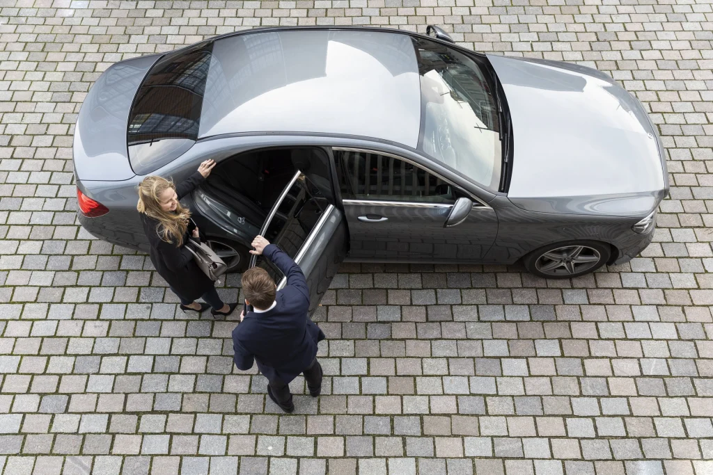 Bovenaanzicht van een chauffeur die het portier opent voor een zakelijke passagier