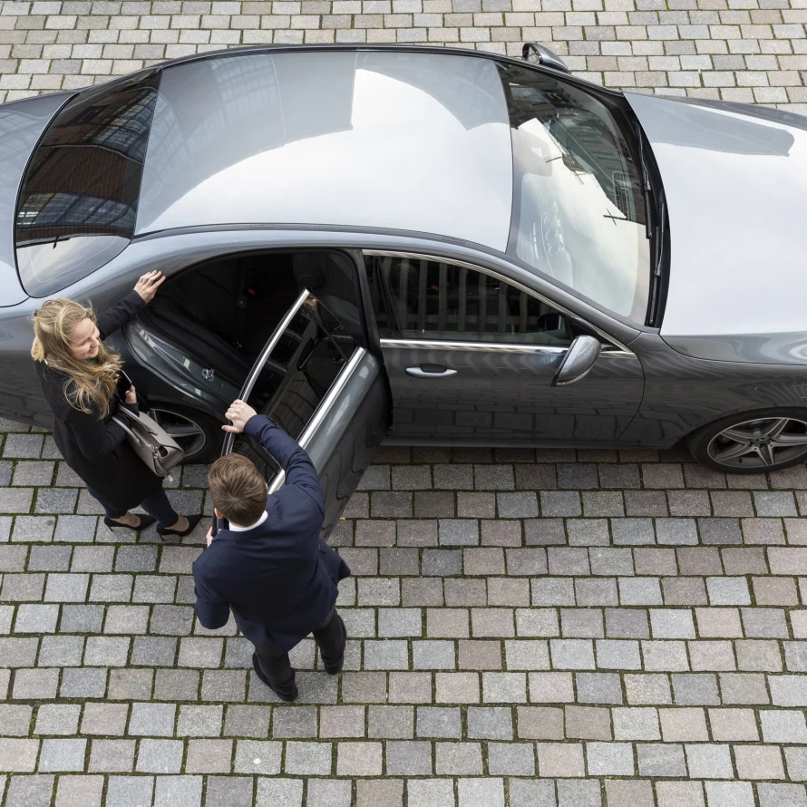 Bovenaanzicht van een chauffeur die het portier opent voor een zakelijke passagier